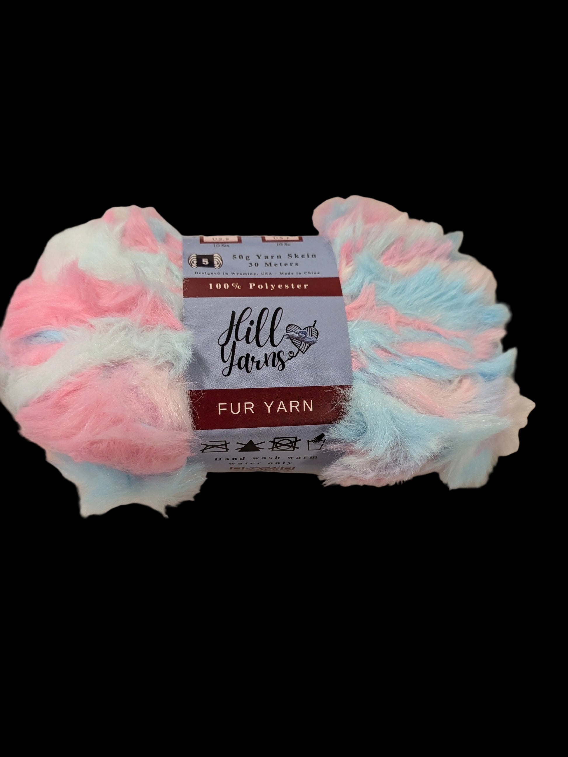 A skein of fluffy pastel fur yarn with pink, light blue, and white marled strands, wrapped with a paper label that reads 'Hill Yarns' and 'Fur Yarn'.